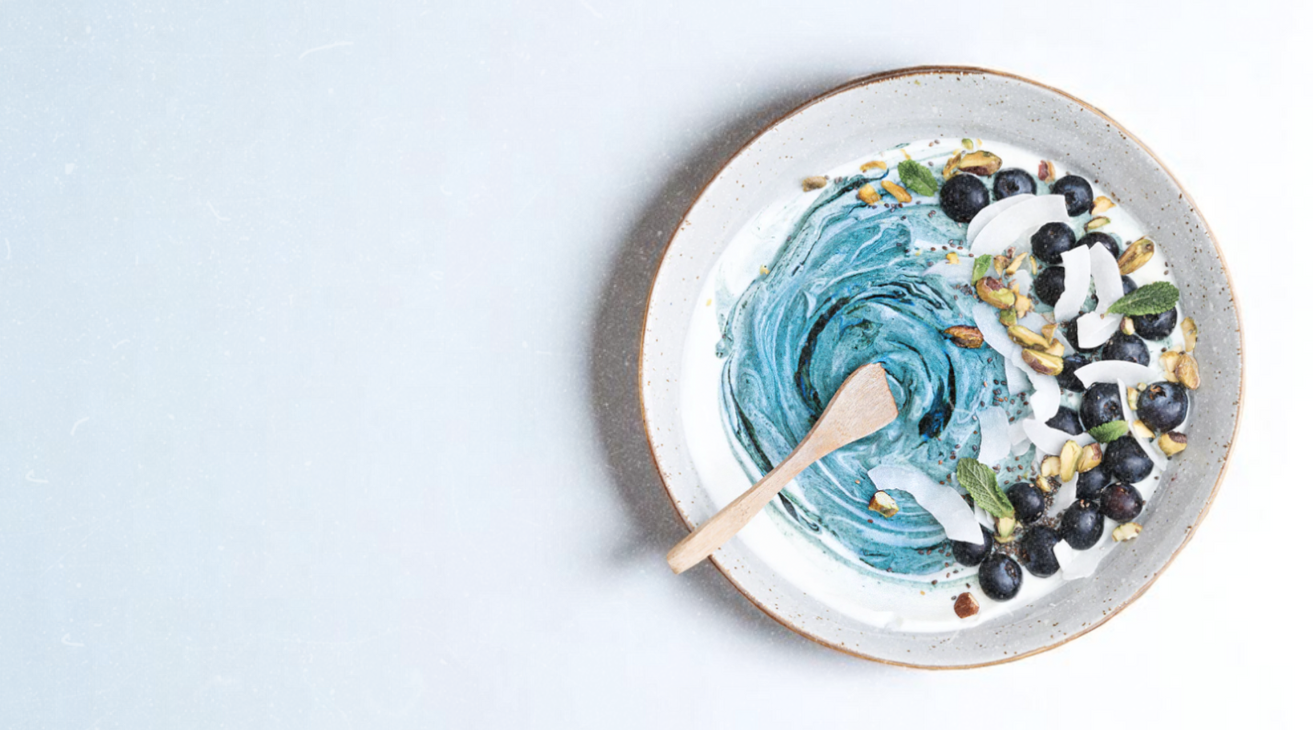 Ocean swirl yogurt bowl topped with pistachios, coconut flakes, blueberries, and mint — a nutrient-dense breakfast made with Elyxar by Apotheka Superfoods.