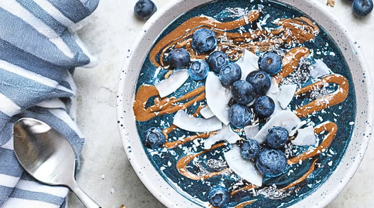 Elyxar smoothie bowl topped with fresh blueberries, almond butter drizzle, coconut flakes, and shredded coconut.