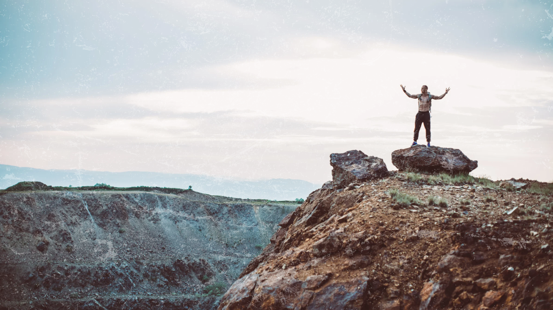Empowered man on rocky summit under sunrise sky — representing the strength, clarity, and resilience fueled by Apotheka Superfoods’ Elyxar.